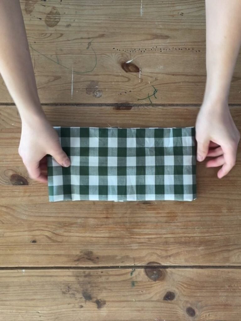 The bow piece neatly folded and prepped, with hands gently adjusting the placement before final assembly.