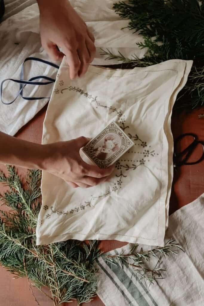 A gift is being laid onto a vintage placemat ready to be wrapped with furoshiki