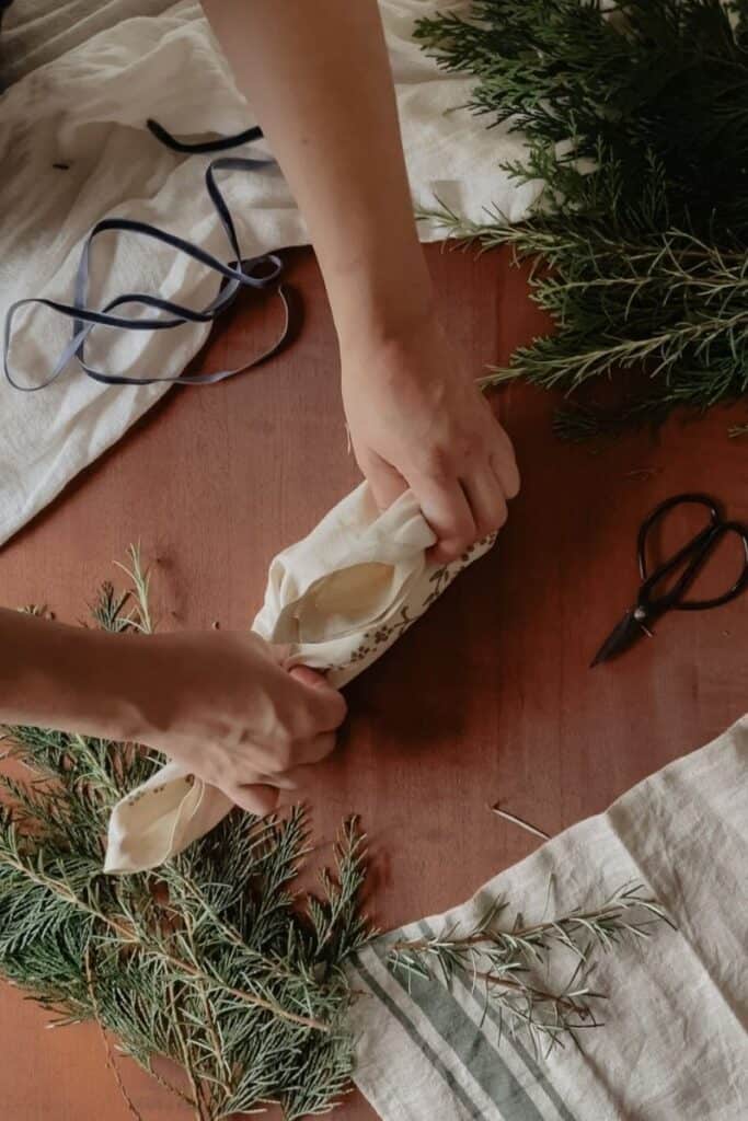 A gift being wrapped using the furoshiki method, using a vintage linen. The other corner has been pinched