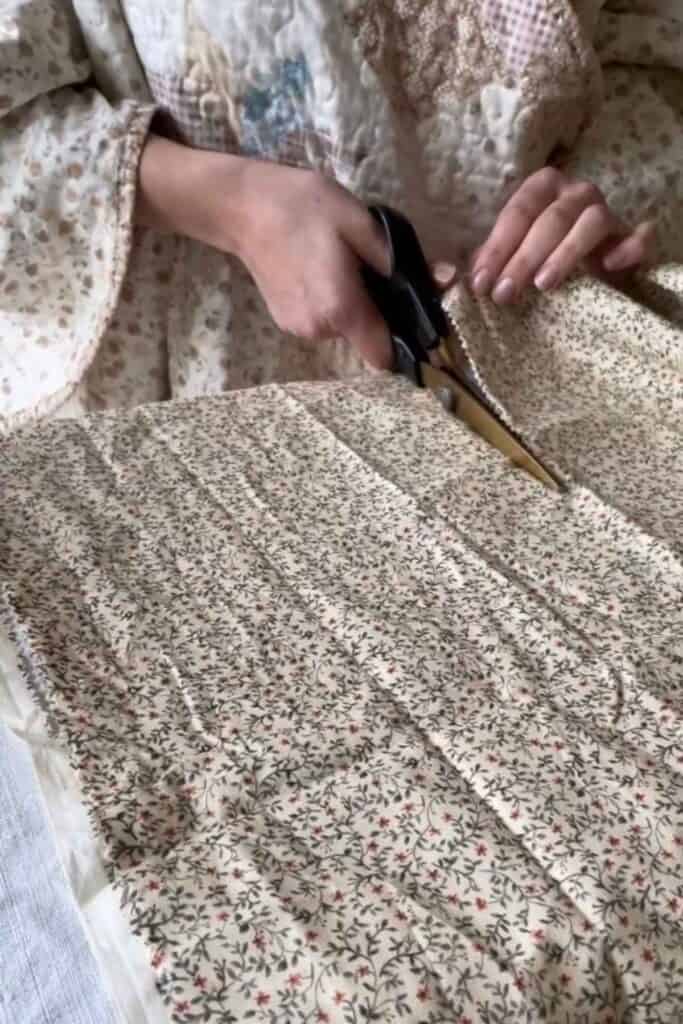 Crafting DIY beeswax wraps, a person expertly cuts floral fabric with pinking shears on the table.