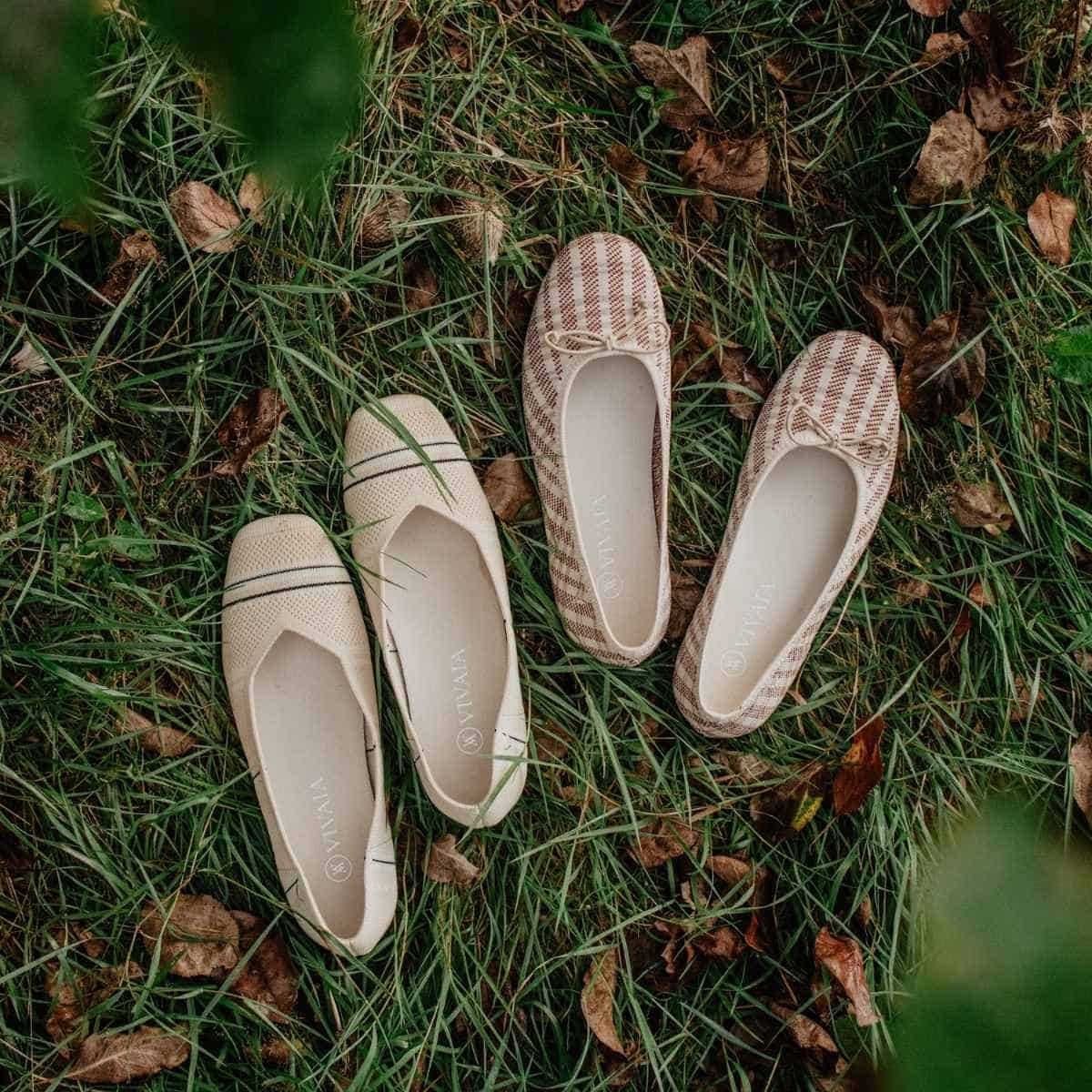 Two pairs of flat shoes lie on grass among fallen leaves, embodying the essence of autumn. The left pair is cream with black trim, while the right is red and white checked. This cozy scene reminds us that seasonal transitions are a perfect time for thoughtful shoe care.