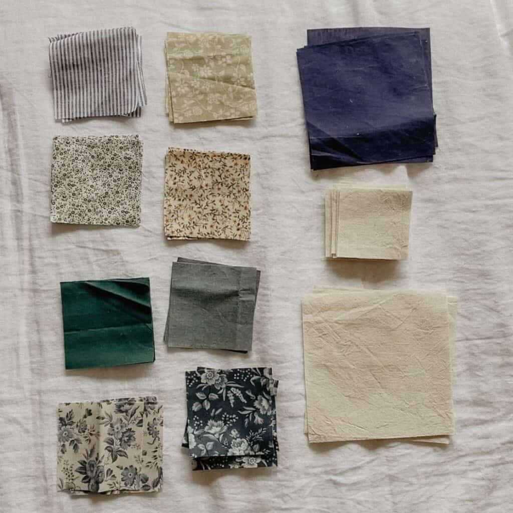 A collection of vintage and deadstock fabric squares arranged on a light background. The squares vary in color and pattern, including floral, striped, and solid designs in shades of green, blue, cream, and gray.