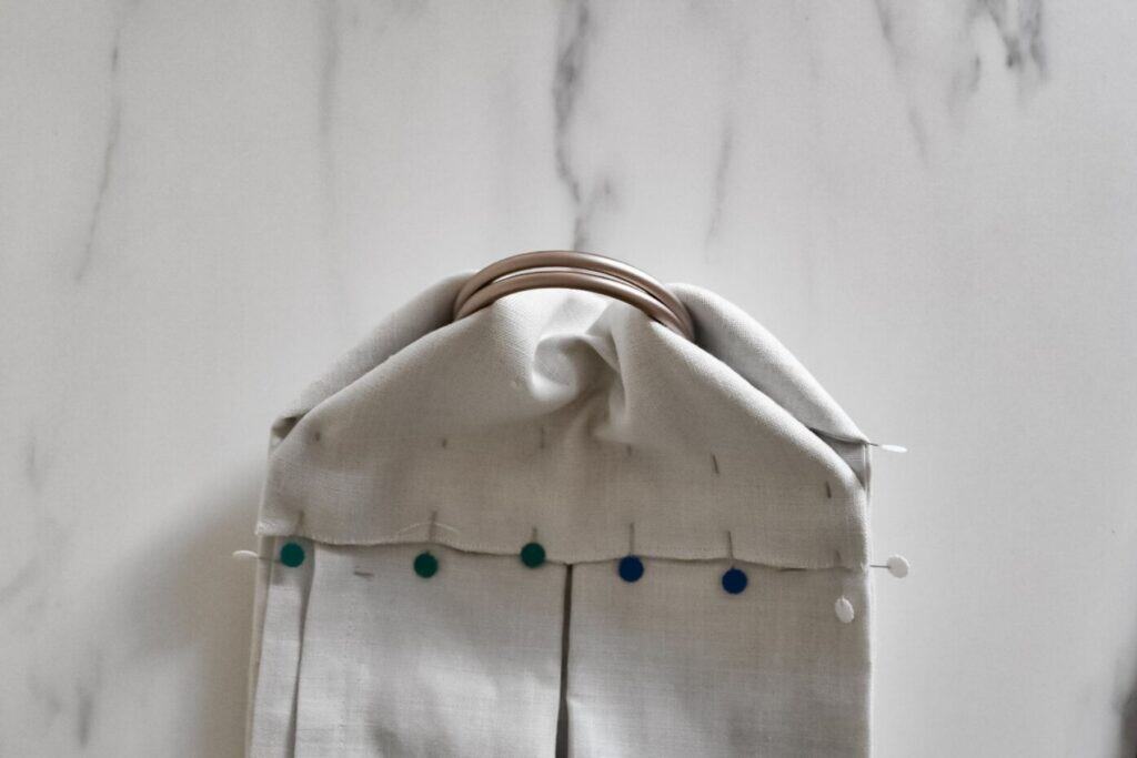 The overlocked edge is folded down and pinned to the rest of the sling, to hold the sling ring in place.