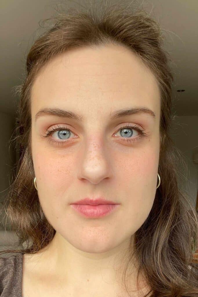 Portrait of a person with long, wavy brown hair and blue eyes, showing the impact of Feel Pro Collagen on her skin. Fine lines have been reduced and her skin looks brighter.
