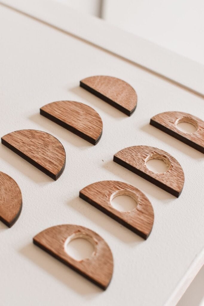 Wooden semicircles with small circular cutouts are neatly arranged on a white surface, ready for adding to the IKEA Kallax hack. The pieces, displayed in two rows, showcase their smooth finish and natural wood grain.
