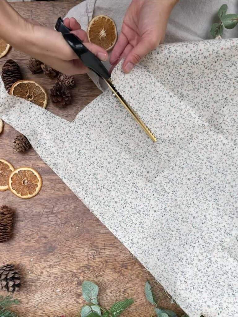 A person cutting floral Christmas fabric with fabric shears