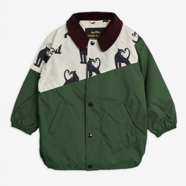 Green Mini Rodini jacket with brown corduroy collar and white yoke featuring a black cat pattern. The jacket has a button-up front and elastic cuffs.