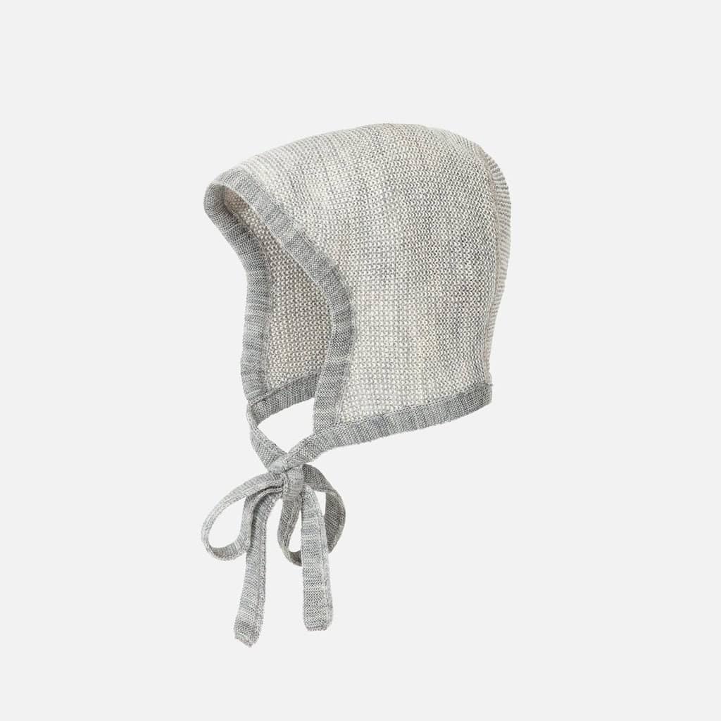 A knitted, light gray wool baby bonnet by Disana with a soft, textured fabric. It features a rounded shape and ties under the chin for secure fastening. The bonnet has a simple, classic design.