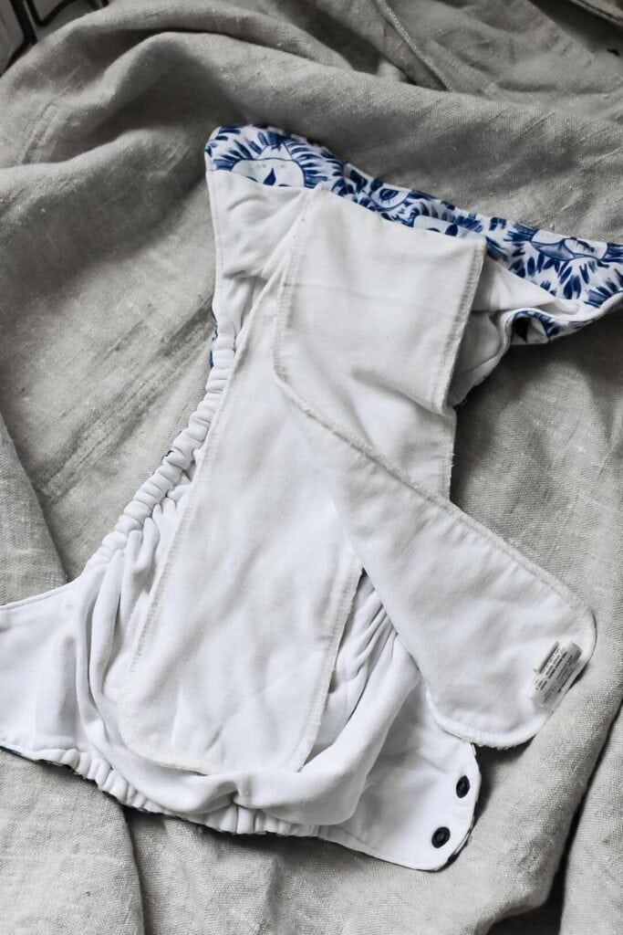 A Thirsties All-in-One cloth nappy lies open showing the different types of absorbent layers within the nappy.